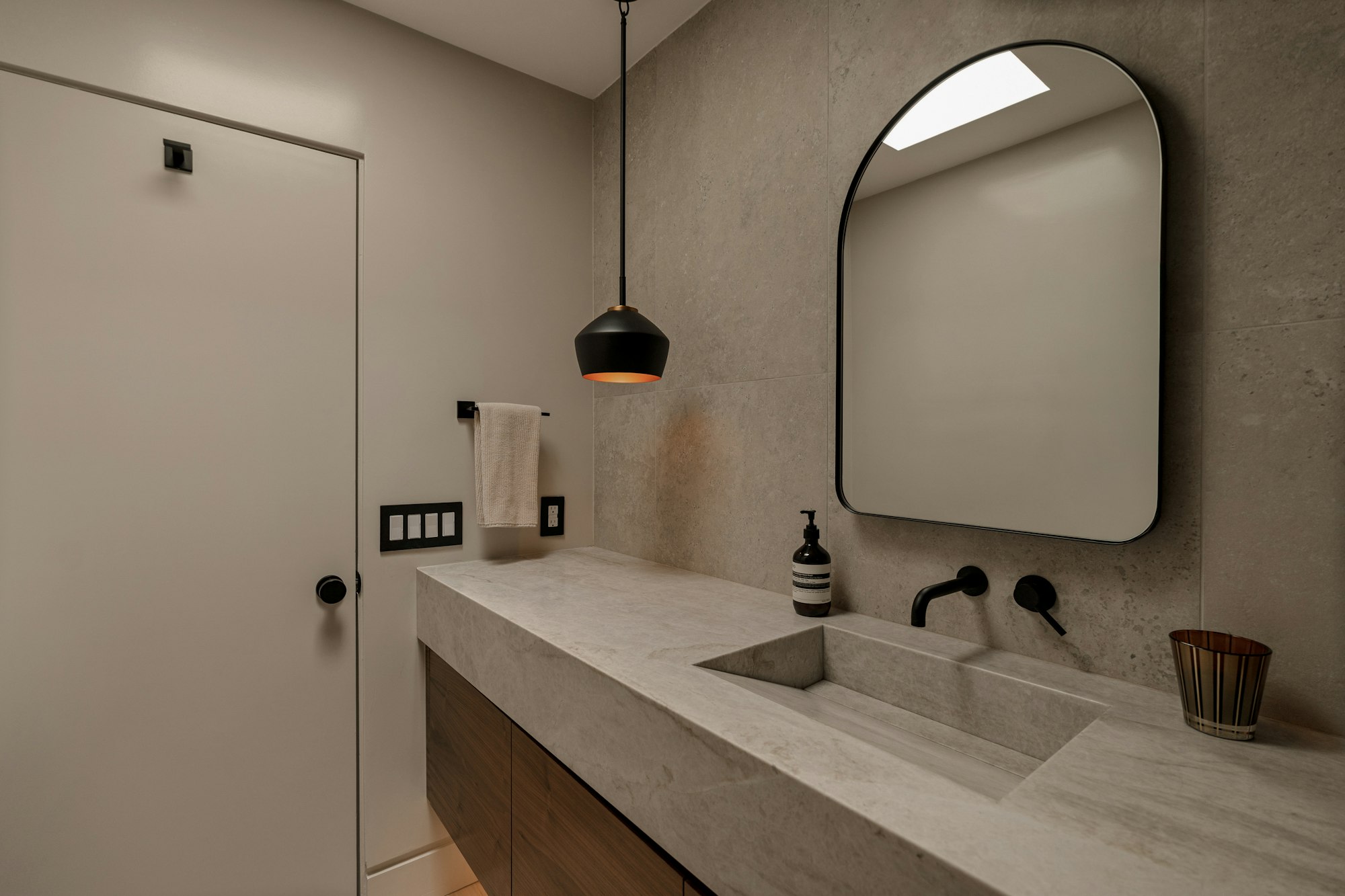 Baño con espejo de arco y lavabo de piedra
